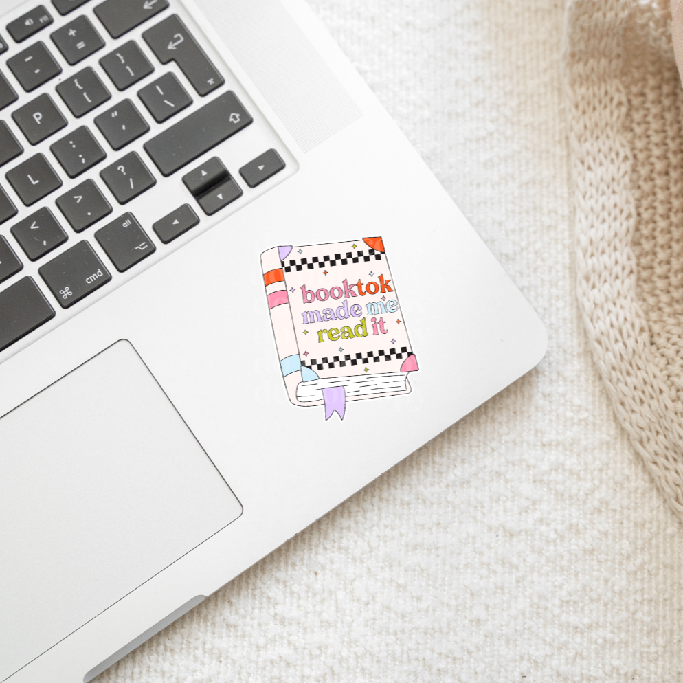 Laptop with a 'booktok made me read it' sticker on a textured surface