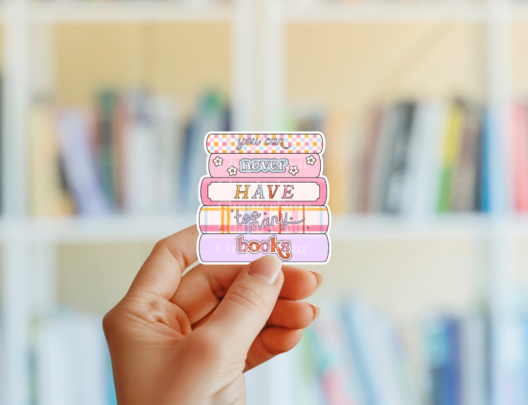 Hand holding a colorful sticker with text in front of a blurred bookshelf