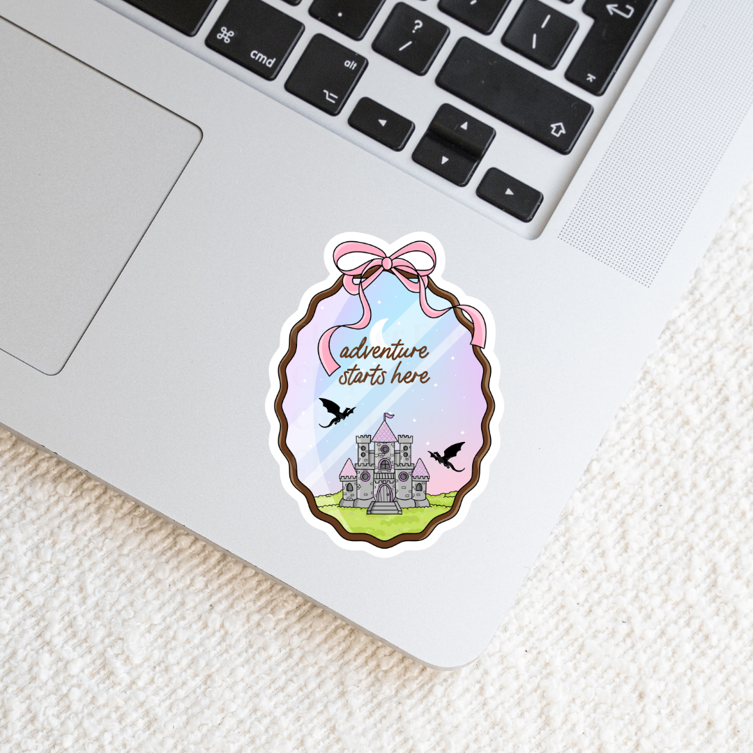 Sticker with castle design and 'adventure starts here' text on a laptop