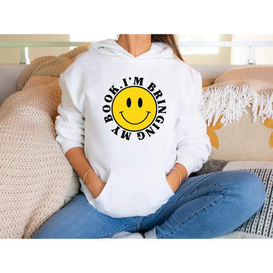 White Gildan 18500 Hoodie. Large yellow face with a smile. Font around the face is black and says I'm Bringing My Book.