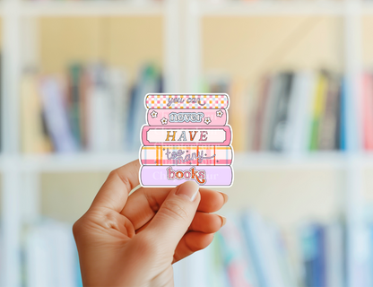 Hand holding a colorful sticker with text in front of a blurred bookshelf