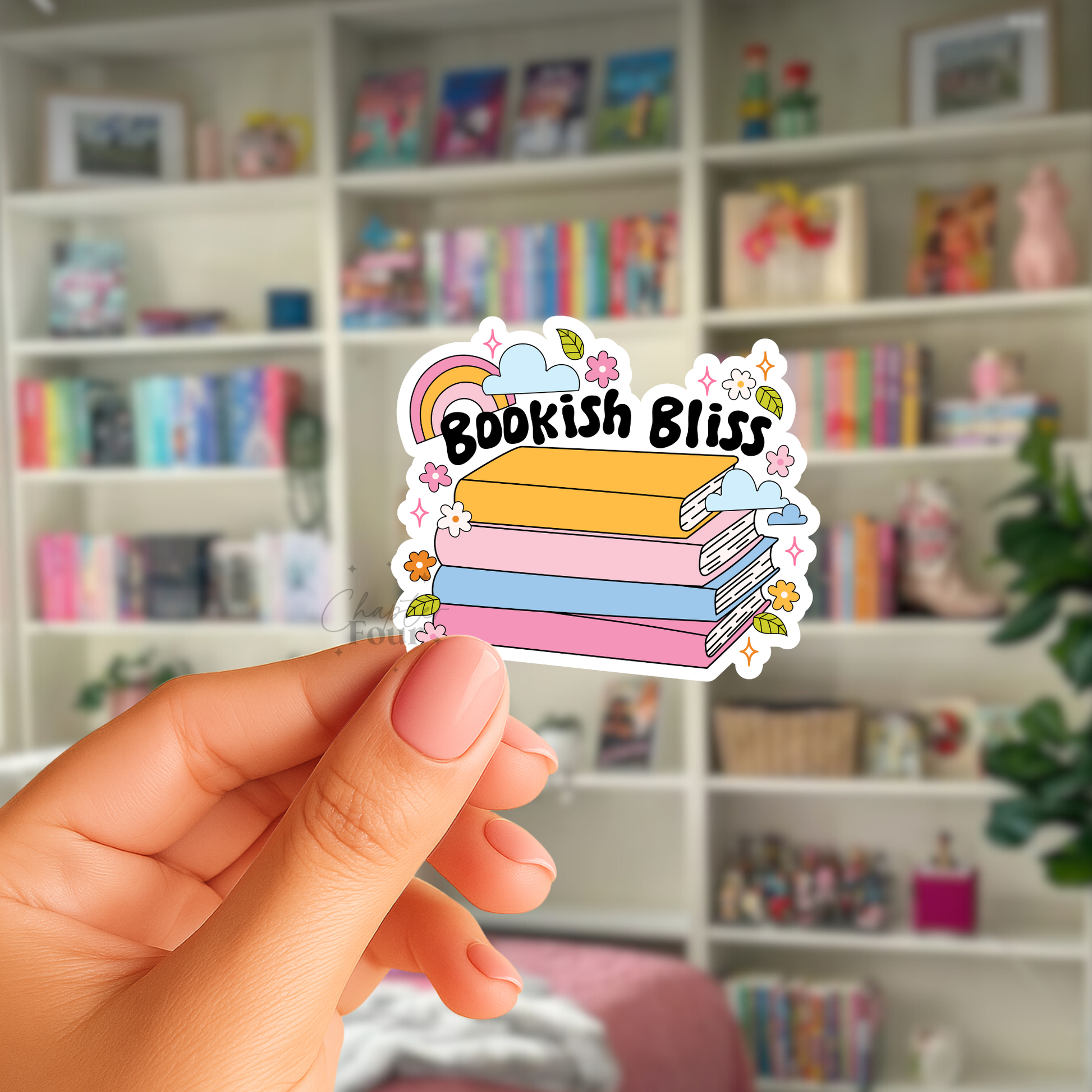 Hand holding a 'Bookish Bliss' sticker with a book design against a blurred bookshelf background.