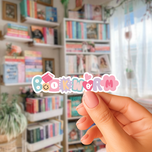 Hand holding a colorful 'Bookworm' sticker in front of bookshelves