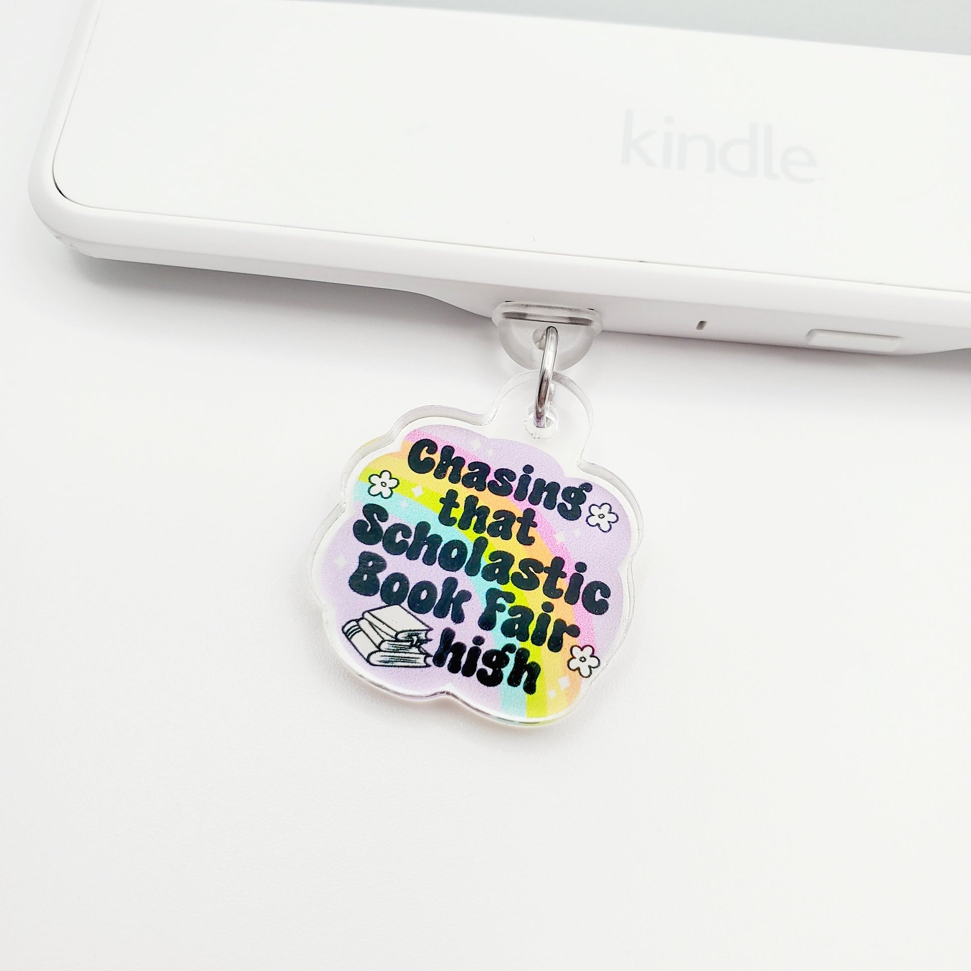 Colorful charm with 'Chasing that scholastic book fair high' text, laying on a white surface