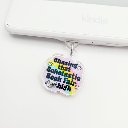 Colorful charm with 'Chasing that scholastic book fair high' text, laying on a white surface