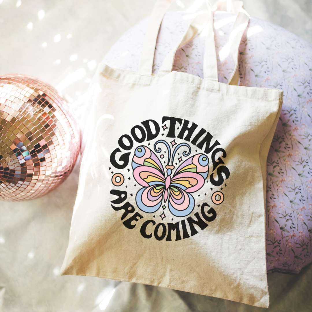 Tote bag with 'Good things are coming' and butterfly design on a glittery surface