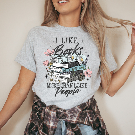 A person wearing a sports gray t-shirt with the text 'I LIKE Books more than People' accompanied by a graphic of books and flowers.