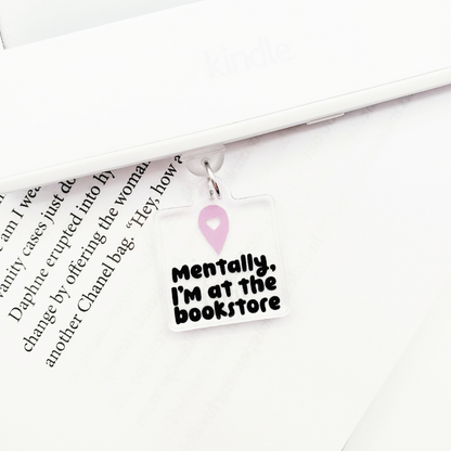 Dust plug charm with 'Mentally, I'm at the bookstore' text, laying on a book page