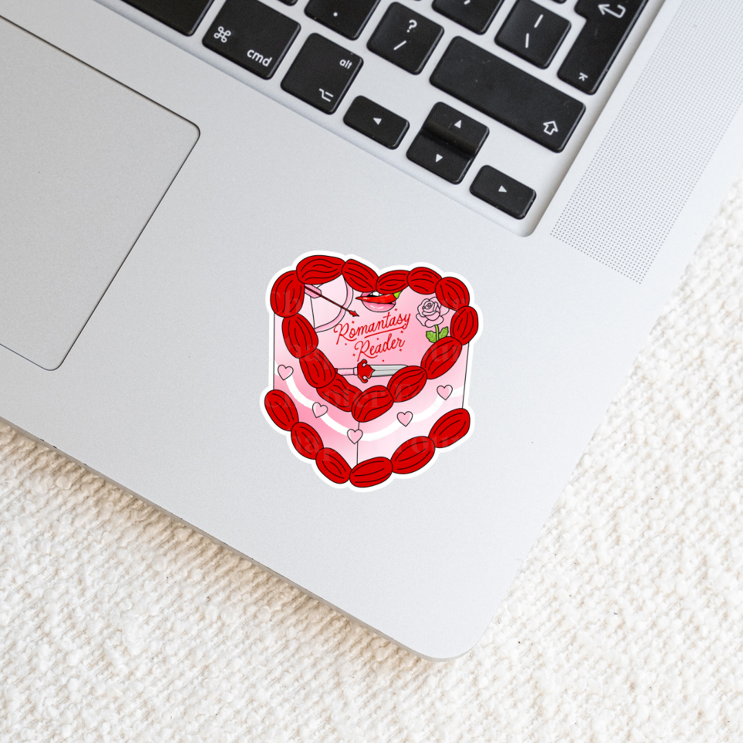 Heart-shaped cake sticker with 'Romantasy Reader' text on laptop 