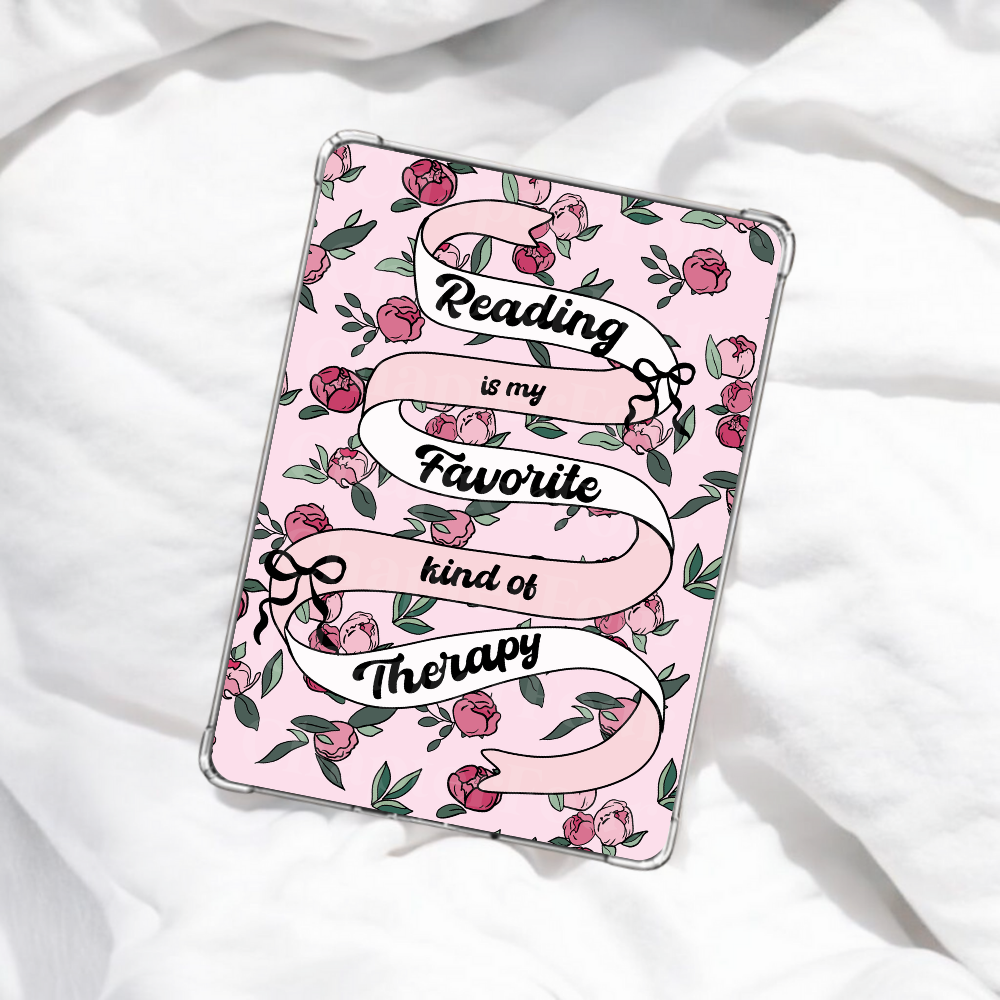 Pink e-reader insert with floral design and text 'Reading is my favorite kind of therapy' laying on white blanket