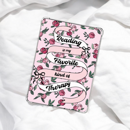 Pink e-reader insert with floral design and text 'Reading is my favorite kind of therapy' laying on white blanket