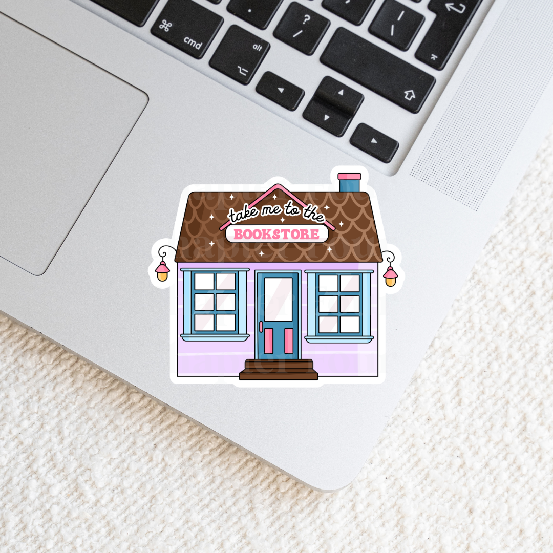 Sticker of a bookstore with 'take me to the bookstore' text, laying on a laptop keyboard