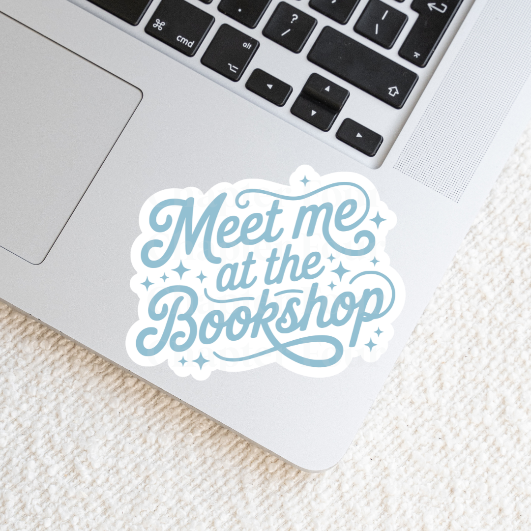 Sticker with 'Meet me at the Bookshop' in blue text, laying on a laptop
