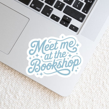 Sticker with 'Meet me at the Bookshop' in blue text, laying on a laptop