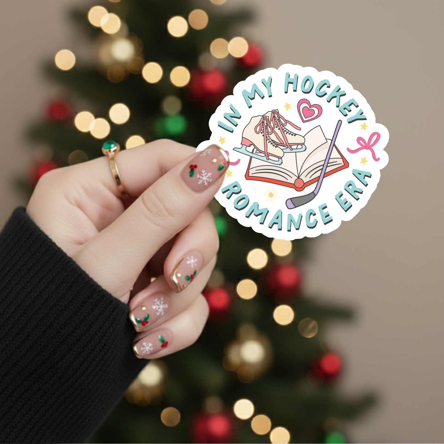 Hand holding a 'In My Hockey Romance Era' sticker with a blurred Christmas tree in the background