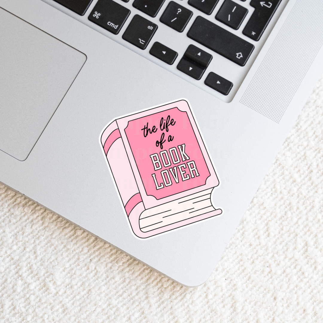 Sticker with pink book-shaped design 'the life of a book lover' text on a laptop