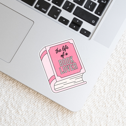 Sticker with pink book-shaped design 'the life of a book lover' text on a laptop